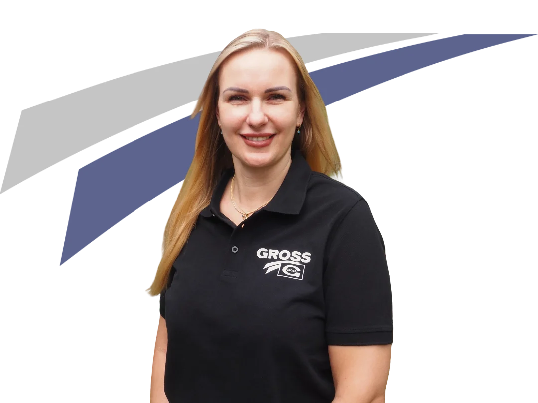 Frau mit blonden Haaren trägt ein schwarzes Poloshirt mit dem Aufdruck „GROSS“ vor einem grafischen, farbigen Hintergrund.