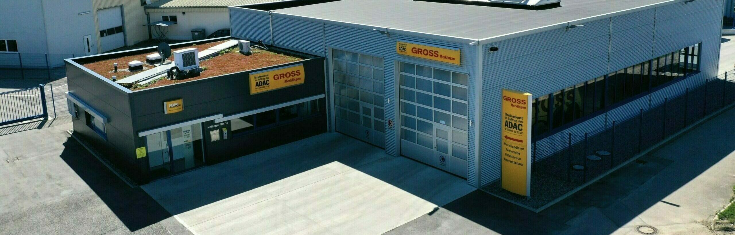 Industriegebäude mit ADAC- und GROSS-Logos, flaches Dach, umlaufender Zaun und breite Garagentore, von oben gesehen.
