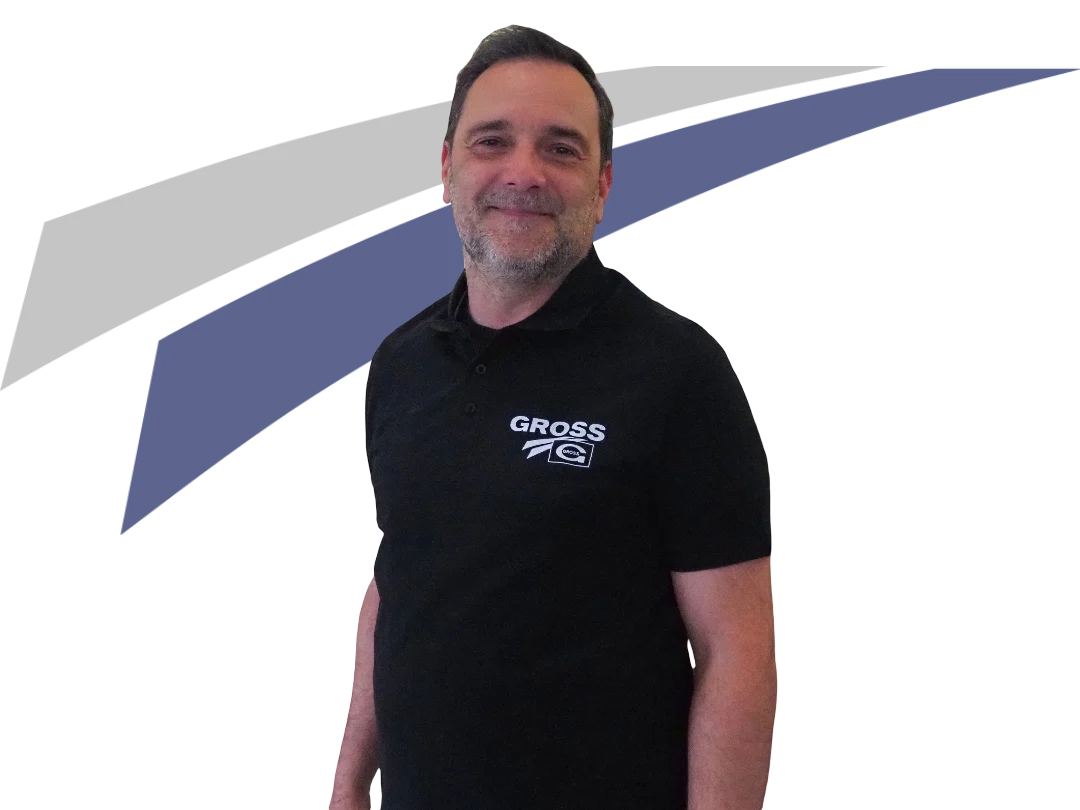 Mann in schwarzem Polo mit GROSS-Logo steht vor einem abstrakten, farbigen Hintergrund. Lächelnd, freundlich.