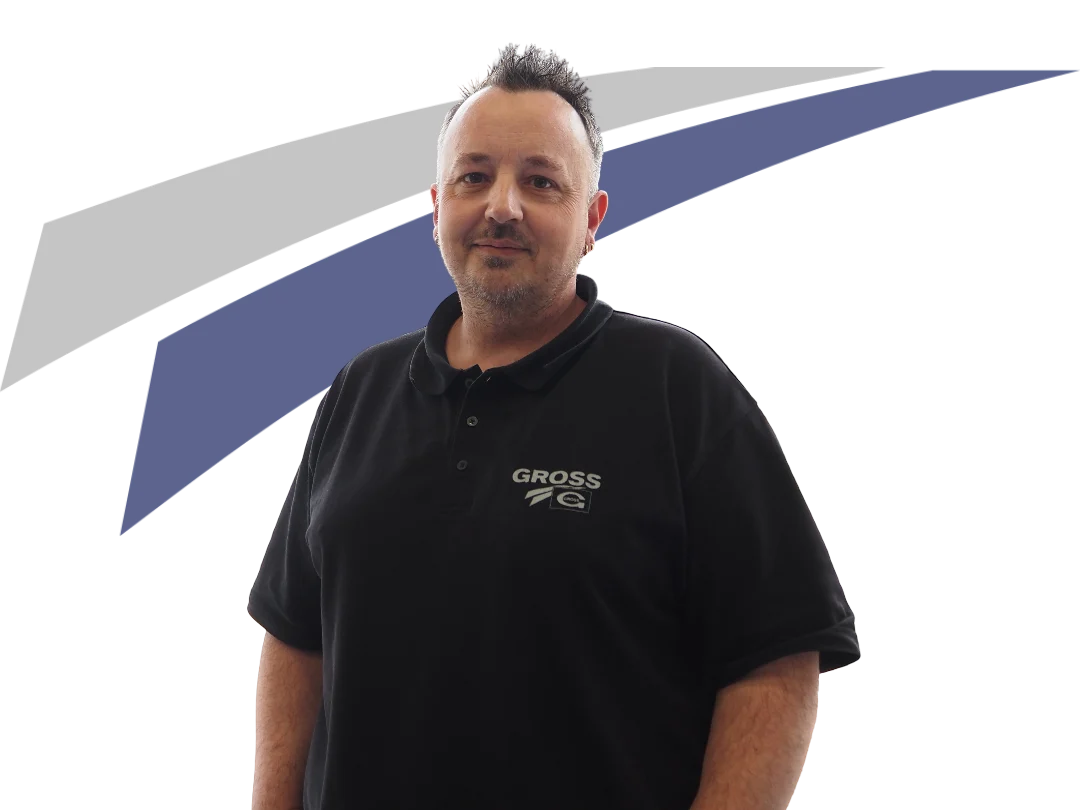 Ein Mann in schwarzem Polo-Shirt mit Logo steht vor einem grafischen Hintergrund in Blau und Grau.