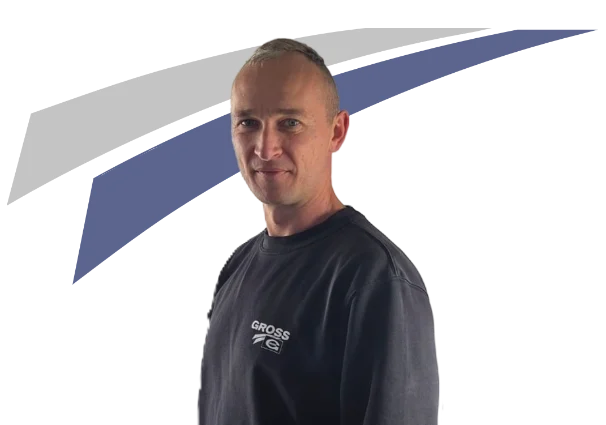 Mann mit kurzer Frisur trägt ein schwarzes Sweatshirt mit Aufdruck, steht vor einem grafischen Hintergrund in Blau und Grau.