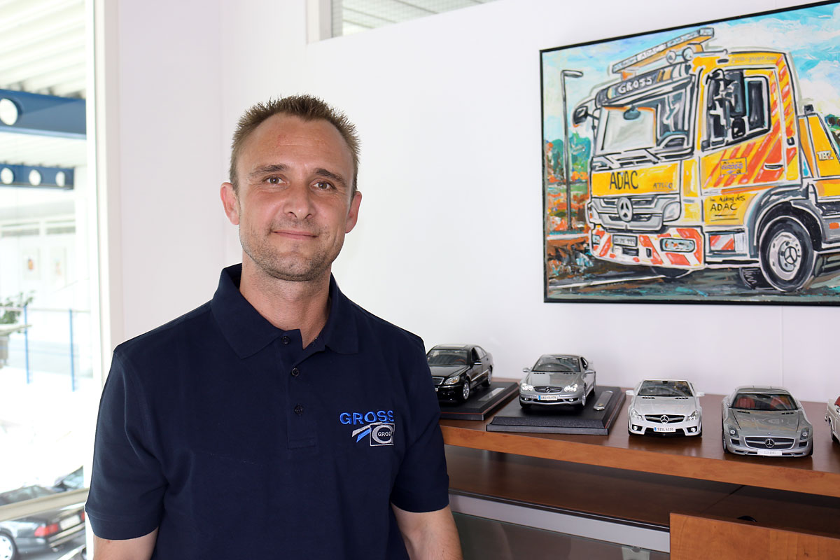 weilheim-lutz-xl Ein Mann in Uniform steht neben Modellautos und einem Gemälde eines ADAC-Abschleppwagens an der Wand.