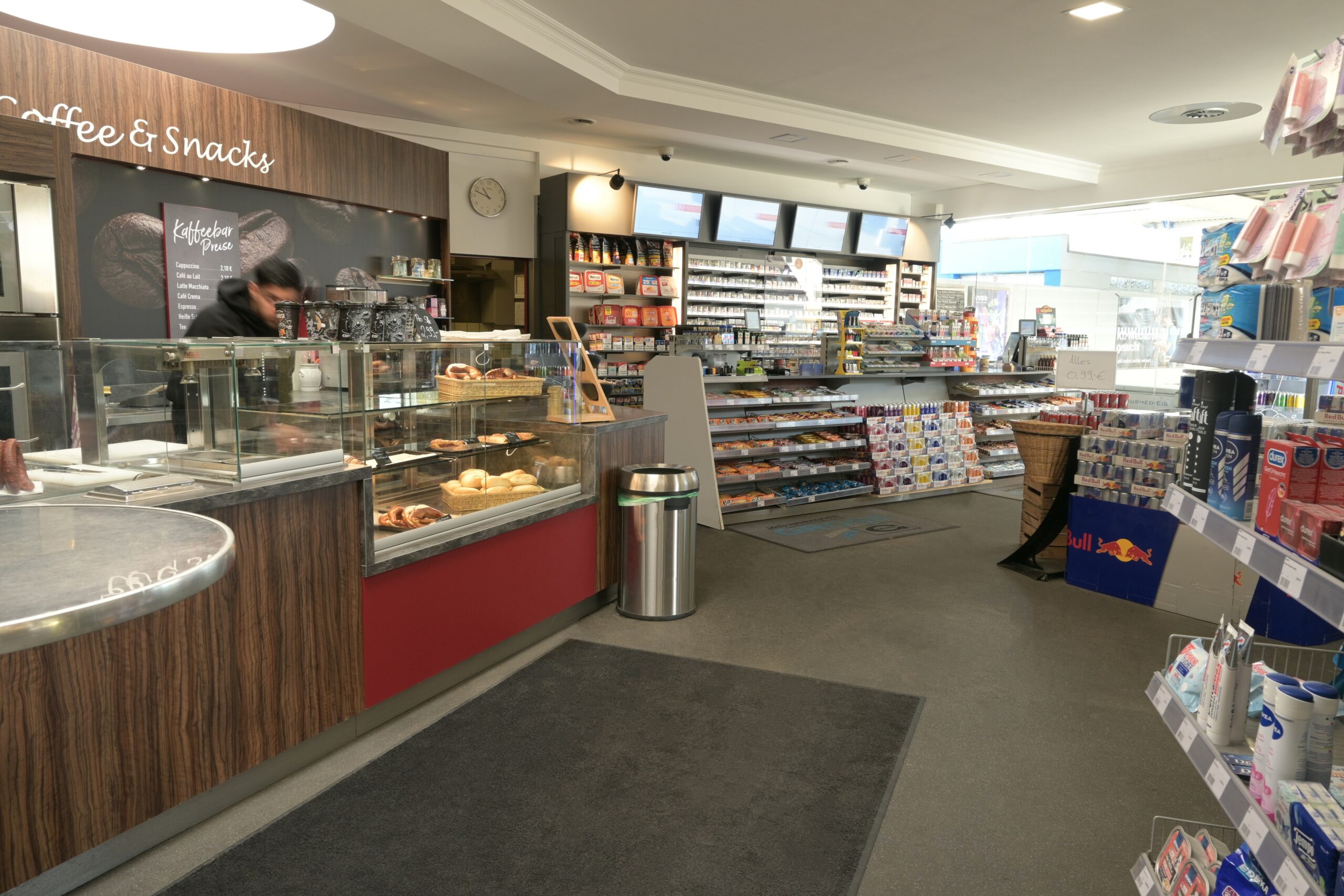 Eingangsbereich eines Kiosk-, Café-, und Verkaufsraums mit Theke, Snacks, Getränken und Regalen mit Produkten.