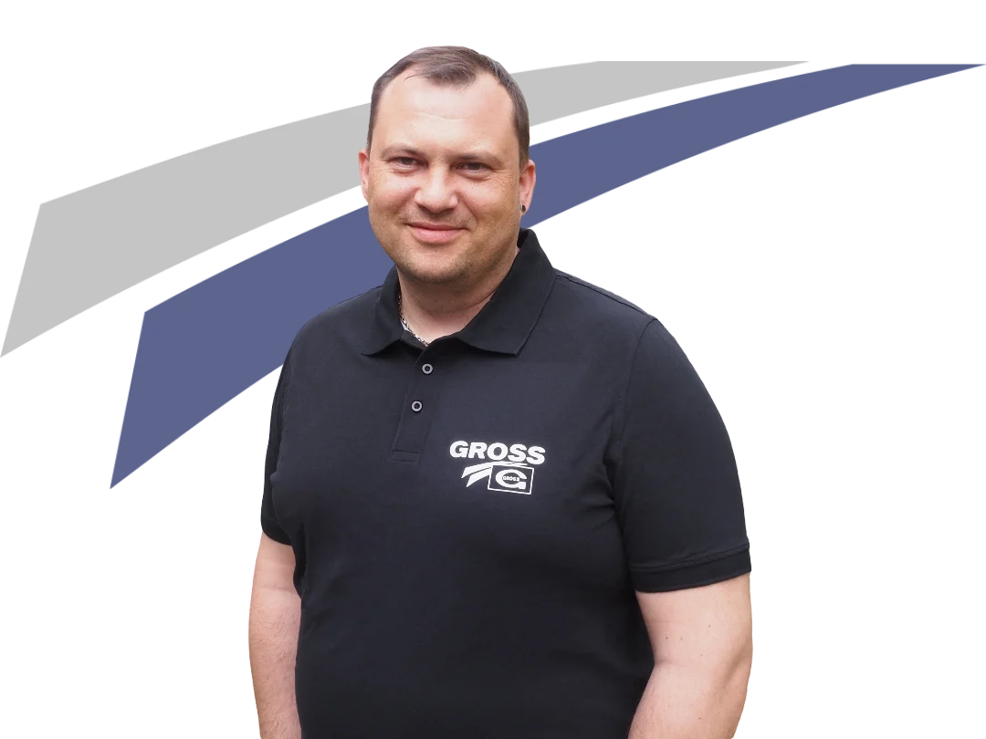 Mann in schwarzer Polo-Shirt mit Logo, lächelt vor einem grafischen Hintergrund in Blau und Grau.