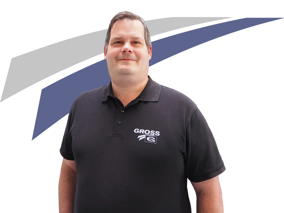 Ein Mann in einem schwarzen Polohemd mit Logo steht vor einem farbigen, abstrakten Hintergrund.