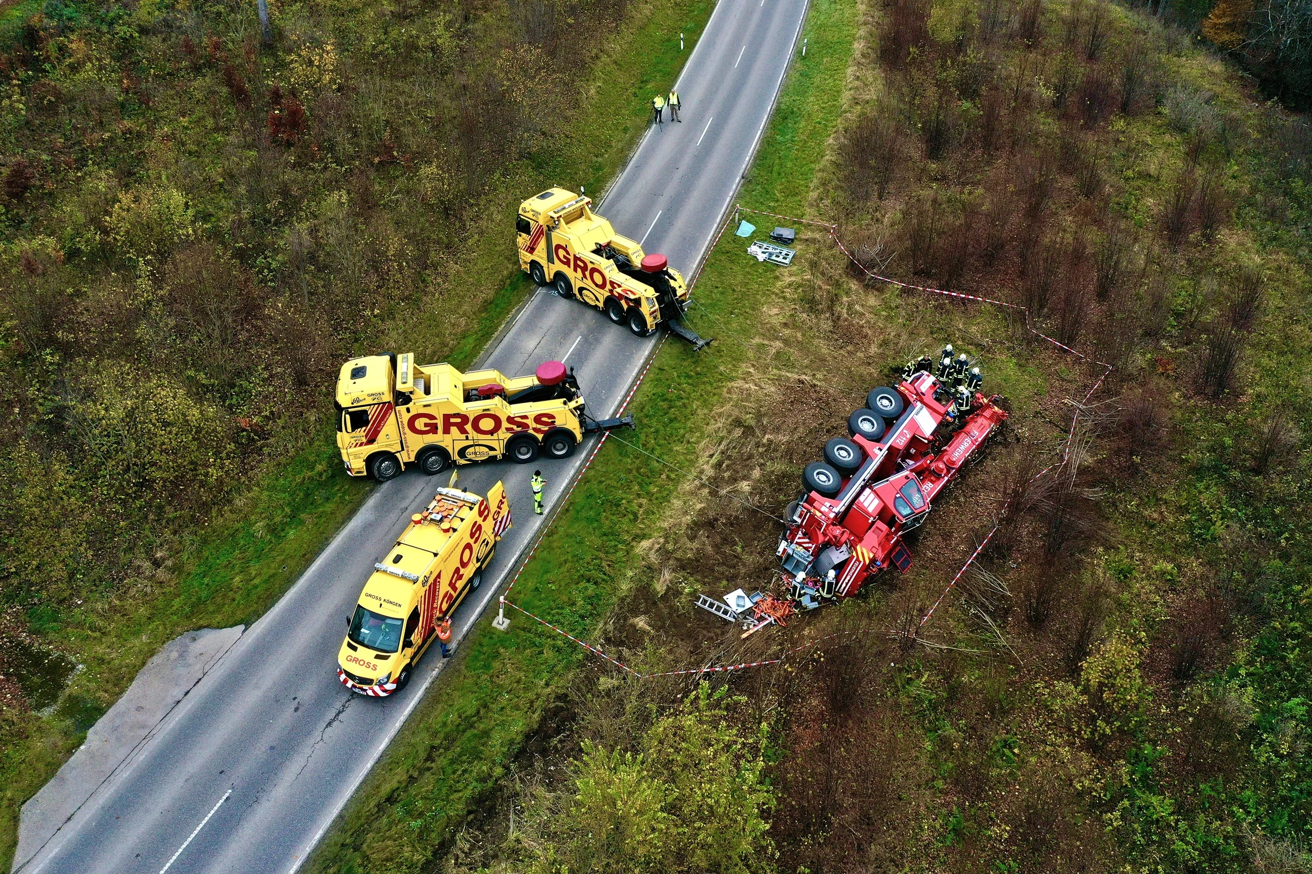 Blick auf einen Unfallort: Zwei gelbe Bergungsfahrzeuge helfen bei der Rettung eines umgestürzten roten Lkw.