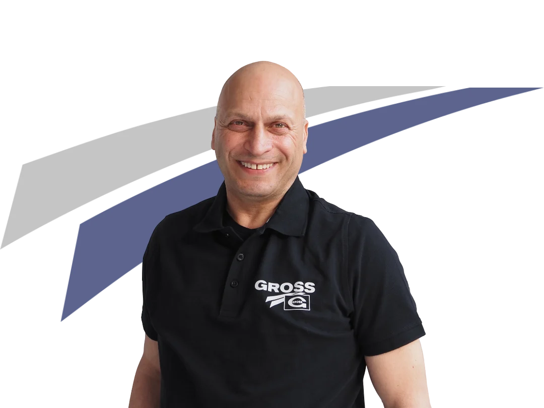 Lächelnder Mann in schwarzem Polohemd mit logo, vor grafischer Hintergrundgestaltung in Blau und Grau.