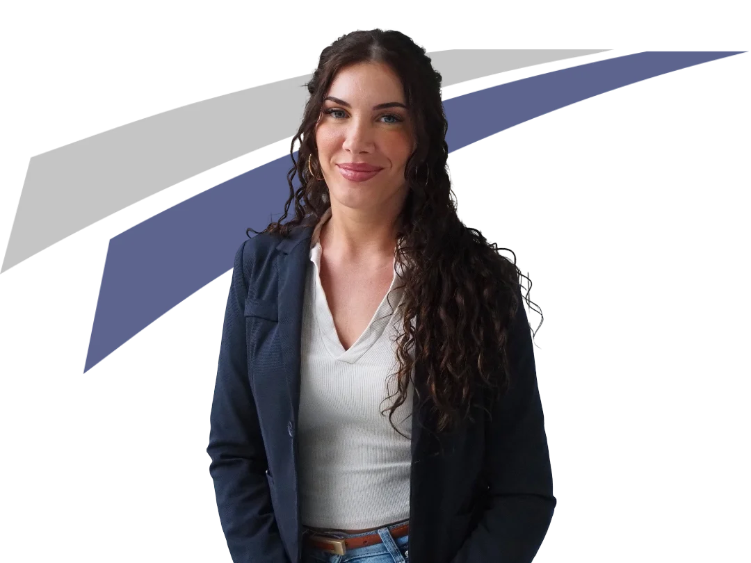 Junge Frau mit lockigem Haar, blauer Blazer und lächelndem Gesicht, vor grafischem, farblich abgesetztem Hintergrund.