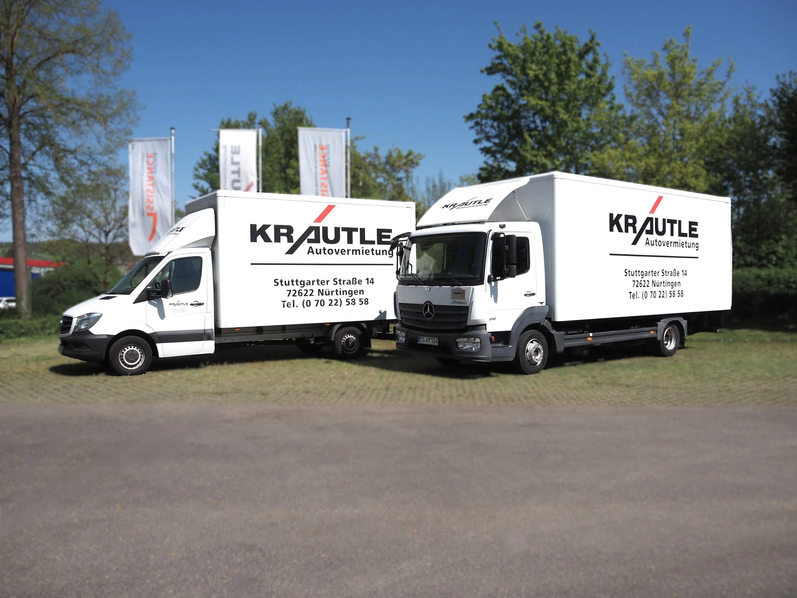 Zwei Miettransporter der Firma Krautle auf einer Wiese, mit auffälligem Firmenlogo und Kontaktdaten sichtbar.