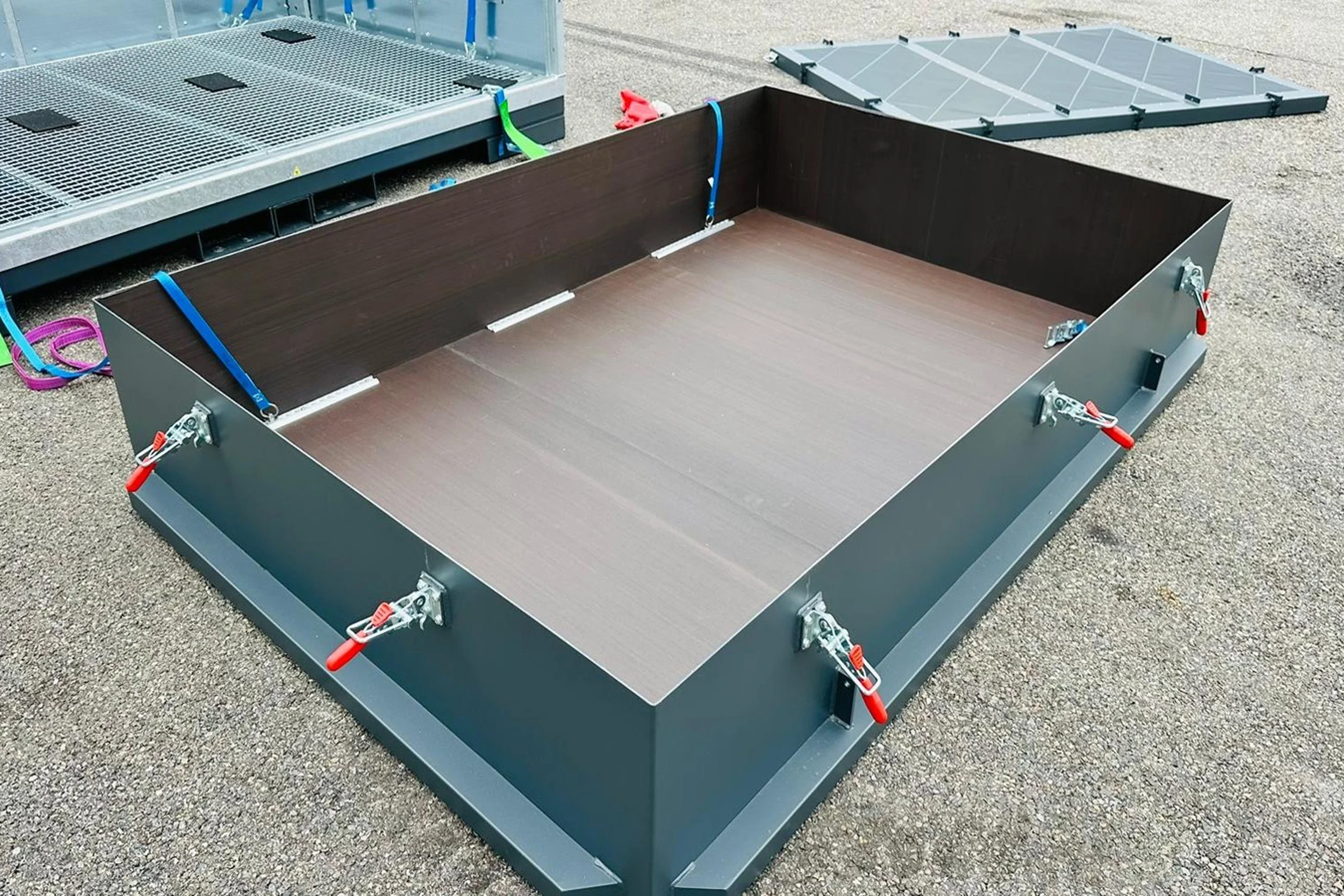 Montierte Metallbox mit Halterungen auf glattem Untergrund, teilweise offen für Zugriff auf den Innenraum.